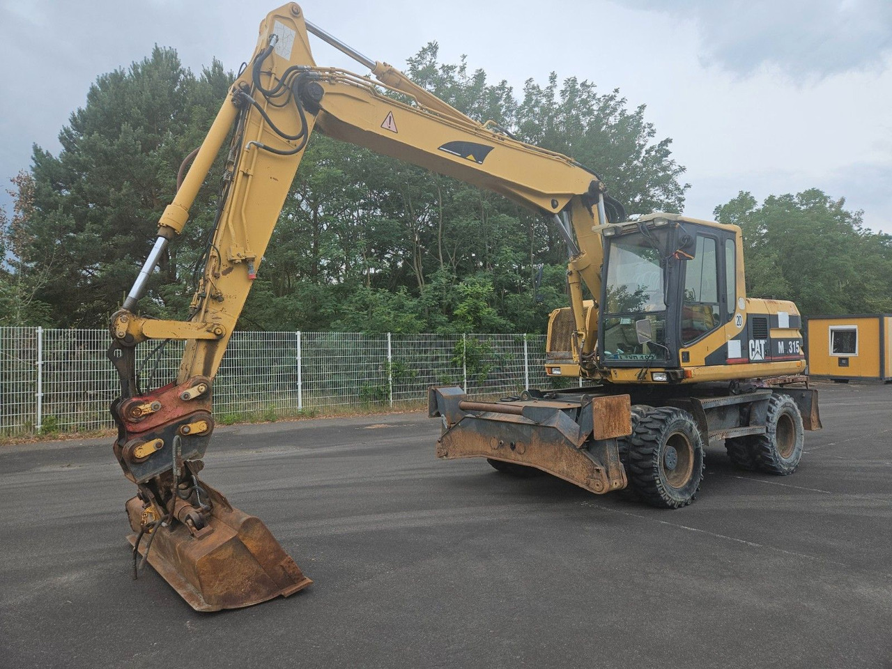 CAT M315 Mobilbagger mit Pratzen und Schild - Riteņu ekskavators: foto 1 CAT M315 Mobilbagger mit Pratzen und Schild - Riteņu ekskavators: foto 1